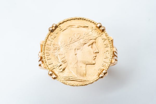 Mesure et art du temps - Ring Coin 20 francs in Yellow Gold 24 Carats Marianne République Française Gold coin of 20 francs 24 carats mounted in ring, setting in Yellow Gold 18 carats. On the front : right profile of the Marianne wearing the phrygian cap and a crown of oak branch. Inscription : FRENCH REPUBLIC. On the reverse side the French motto : Liberty, equality, fraternity surrounds a rooster, date 1907. Engraver : Jules-Clément Chaplain. Edge with inscription LIBERTE EGALITE FRATERNITE. Mounting punched eagle head Size : 71,5 FR; 13,75 US. Bijoutier - Joaillier - Bijoux anciens - Horloger - Bretagne - Morbihan - France - Vannes